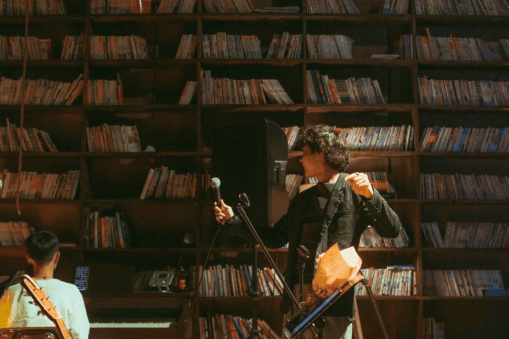 Quán cà phê Đà Lạt nổi bật với kệ sách khổng lồ cùng những đêm nhạc acoustic du dương từ các nghệ sĩ biểu diễn (Nguồn: Fanpage Fong)